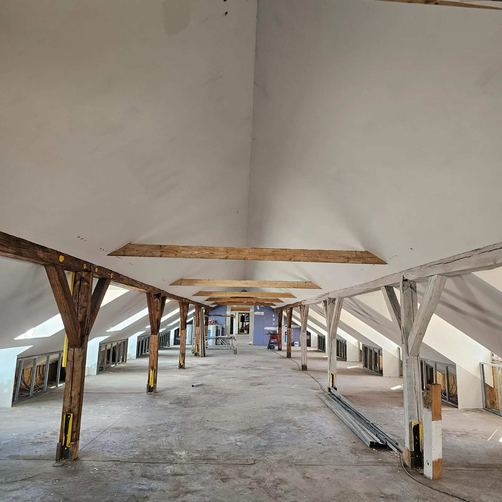 Dachgeschossausbau: langer Dachboden mit geschlossenen Schrägen und freigelegtem Holztragwerk