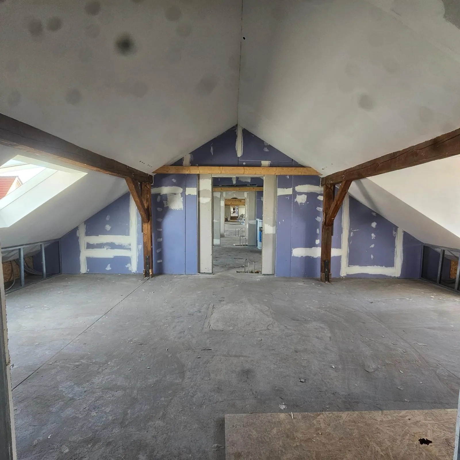 Dachgeschossausbau: beplanktes Dachzimmer mit sichtbaren Holzbalken